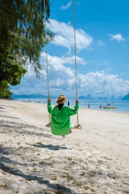 Phuket Tayland yakınlarındaki tropikal ada Naka Adası sahilinde bir kadın, Tayland 'da salıncakta sallanan bir kadın.