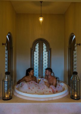 Gül yapraklı romantik bir küvet, jakuzide lüks bir tatil, tatil sırasında lüks bir otelde banyo küvetinde birkaç erkek ve kadın.