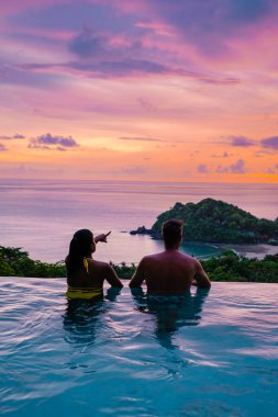 Tayland 'da sonsuz havuzda, okyanusa bakan bir çift Avrupalı erkek ve Asyalı bir kadın Tayland' da lüks bir tatil. Phuket