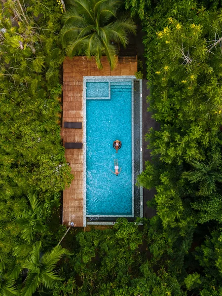 aerial drone view of swimming pool in the jungle of Krabi Thailand, aerial view with a drone above swimming pool in the jungle of Thailand. couple men and woman in pool from above