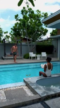 Havuz villasında lüks bir tatil yapan iki erkek ve kadın. Erkekler ve kadınlar yüzme havuzunda