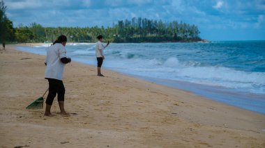İnsanlar Phuket Tayland sahilindeki plastik çöpleri temizliyor..
