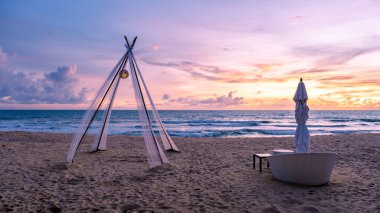 Phuket Tayland sahilinde gün batımı, renkli günbatımı muson yağmurları sırasında plajda lüks sahil yatağı