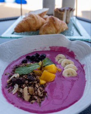 Meyve ve müsli kırmızı pancar yoğurdu, Phuket Tayland 'da kumsalda kahvaltı, yemek ve tropikal deniz manzaralı lüks bir kahvaltı masası, lüks seyahat ve yaşam tarzı.. 