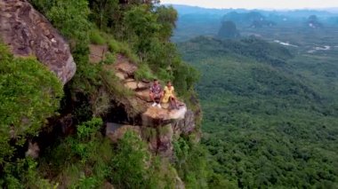 Ejderha Tepesi dağı Krabi Tayland, genç bir gezgin uçurumun üzerindeki kayanın üzerinde oturuyor, güzel bir manzarası var. Tayland, Krabi 'deki Khao Ngon Nak Doğa Yolu' nda Ejder Tepesi veya Khuan Sai.