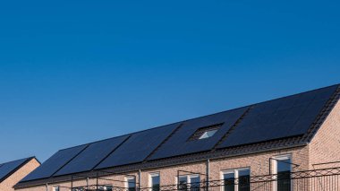 Güneşli bir gökyüzüne bağlı güneş panelleri olan yeni evler inşa edin. Siyah güneş panelleri olan yeni binaları kapatın. Zonnepanelen, Zonne enerjisi, Çevirisi: Güneş paneli, Güneş Enerjisi. 