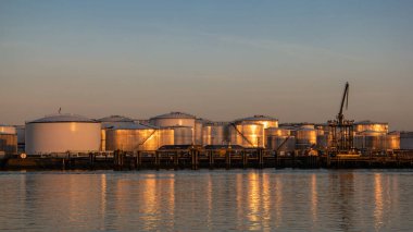 Rotterdam Netherlands, Oil harbor with tank terminals and chemical carriers in the port of Rotterdam during sunrise in the harbor, huge oil tanks to store gas and oil