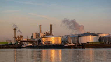 Rotterdam Netherlands, Oil harbor with tank terminals and chemical carriers in the port of Rotterdam during sunrise in the harbor, huge oil tanks to store gas and oil