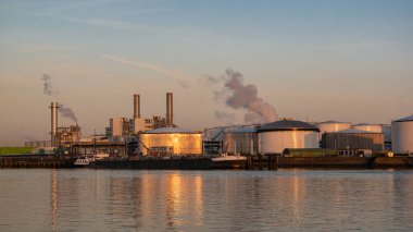 Rotterdam Netherlands, Oil harbor with tank terminals and chemical carriers in the port of Rotterdam during sunrise in the harbor, huge oil tanks to store gas and oil