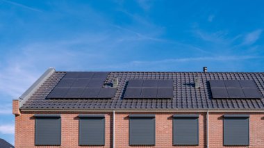 Güneşli bir gökyüzüne bağlı güneş panelleri olan yeni evler inşa edin. Siyah güneş panelleri olan yeni binaları kapatın. Zonnepanelen, Zonne enerjisi, Çevirisi: Güneş paneli, Güneş Enerjisi. 