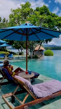 Lüks bir otelin sonsuz havuzunun kenarında kokteyller. Renkli meyve kokteylleri, havuzda dinlenen kadın, havuzdaki Asyalı kadın., 