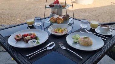 Breakfast on the beach in Thailand, a Luxury breakfast table with food and beautiful tropical sea view background. colorful break fast