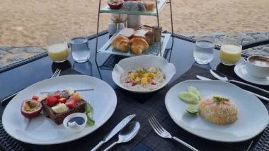 Tayland 'da kumsalda kahvaltı yemek ve tropik deniz manzaralı lüks bir kahvaltı masası. rengarenk kahvaltı