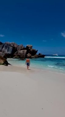 Anse Source dArgent, La Digue Seychelles, Seyşeller 'de lüks bir tatil sırasında tropik bir plajda yaşayan genç bir adam. Tropik sahil Anse Kaynak dArgent, La Digue Seyşeller