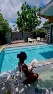 Asyalı kadınlar lüks bir havuz evinde tatil yapıyorlar. Tatilde havuzda yüzen kadın