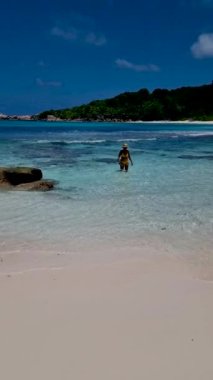 Anse Source dArgent, La Digue Seychelles, Seyşeller 'de lüks bir tatil sırasında tropik bir plajda yaşayan genç bir kadın. Tropik sahil Anse Kaynak dArgent, La Digue Seyşeller