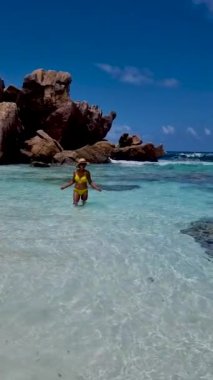 Anse Source dArgent, La Digue Seychelles, Seyşeller 'de lüks bir tatil sırasında tropik bir plajda yaşayan genç bir kadın. Tropik sahil Anse Kaynak dArgent, La Digue Seyşeller