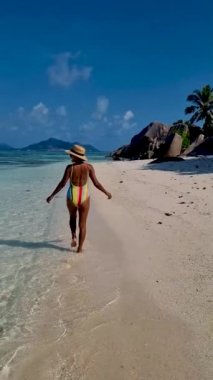 Anse Source dArgent, La Digue Seychelles, Seyşeller 'de lüks bir tatil sırasında tropik bir plajda yaşayan genç bir kadın. Tropik sahil Anse Kaynak dArgent, La Digue Seyşeller