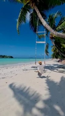 Cote DOr Sahili, Praslin Seyşeller, Seyşeller 'de lüks bir tatil sırasında tropikal plaj. Sahilde salıncakta sallanan Asyalı kadın.