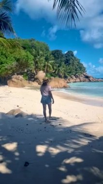 Anse Source dArgent, La Digue Seychelles, Seyşeller 'de lüks bir tatil sırasında tropik bir plajda yaşayan genç bir kadın. Tropik sahil Anse Kaynak dArgent, La Digue Seyşeller