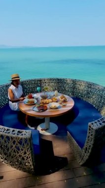 Asian woman having lunch at a restaurant looking out over the ocean of Pattaya Thailand, woman having dinner in a restaurant by the ocean in Pattaya. 
