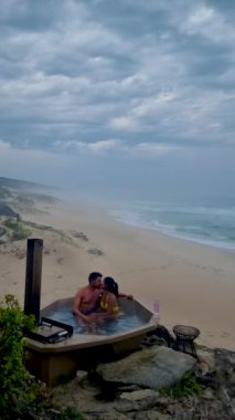 couple in bathtub on the beach of The Hoop nature reserve in South Africa, romantic bath tub with rose petals, luxury vacation in a jacuzzi, couple men and woman in bath tub of a luxury resort 