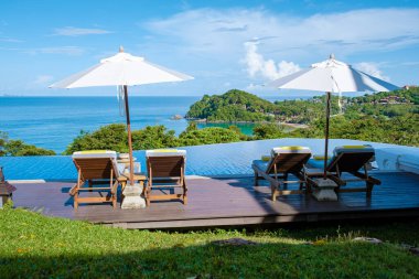 Koh Lanta plajında plaj sandalyeleri, Tayland 'da havuz kenarında şemsiyeli plaj sandalyeleri.