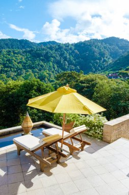 Koh Lanta plajında plaj sandalyeleri, Tayland 'da havuz kenarında şemsiyeli plaj sandalyeleri.