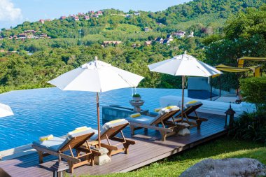 Koh Lanta plajında plaj sandalyeleri, Tayland 'da havuz kenarında şemsiyeli plaj sandalyeleri.