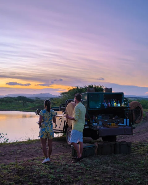 couple men and Asian woman on safari in South Africa, South Africa Kwazulu Natal, luxury safari car during a game drive, couple men and woman on safari in South Africa.