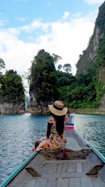 Khao Sok Tayland, Khao Sok Milli Parkı 'ndaki Khao Lan Gölü' ndeki kireçtaşı kayalıkları olan uzun kuyruklu teknedeki kadın.