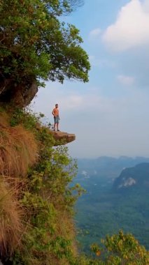 Ejderha Tepesi dağı Krabi Tayland, genç bir gezgin uçurumun üzerindeki kayanın üzerinde oturuyor, güzel bir manzarası var. Tayland, Krabi 'deki Khao Ngon Nak Doğa Yolu' nda Ejder Tepesi veya Khuan Sai.. 