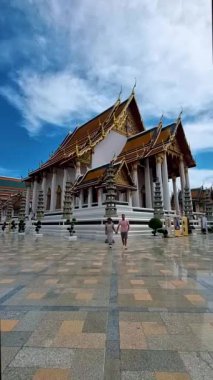 Wat Suthat Thepwararam Ratchaworahawihan is the royal temple in the capital city of Bangkok, Thailand. Couple of European men and Asian woman with hat visit a temple in Bangkok