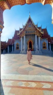 Wat Benchamabophit the marble temple, is a royal temple in the capital city of Bangkok, Thailand. Asian woman with hat visiting a temple in Bangkok