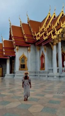 Wat Benchamabophit the marble temple, is a royal temple in the capital city of Bangkok, Thailand. Asian woman with hat visiting a temple in Bangkok