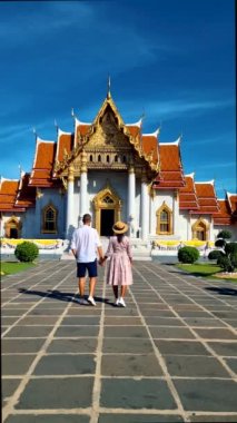 Wat Benchamabophit the marble temple, is a royal temple in the capital city of Bangkok, Thailand. couple Asian women with hat and European men visiting a temple in Bangkok