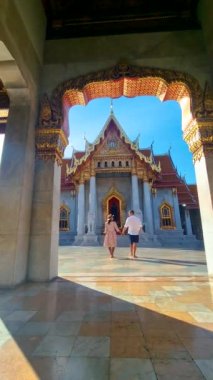Wat Benchamabophit the marble temple, is a royal temple in the capital city of Bangkok, Thailand. couple Asian women with hat and European men visiting a temple in Bangkok