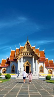 Wat Benchamabophit the marble temple, is a royal temple in the capital city of Bangkok, Thailand. couple Asian women with hat and European men visiting a temple in Bangkok