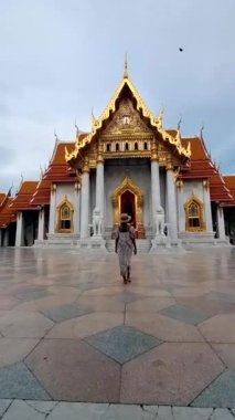 Wat Benchamabophit mermer tapınak, Tayland 'ın başkenti Bangkok' ta bulunan bir kraliyet tapınağıdır. Şapkalı Asyalı kadın Bangkok 'ta bir tapınağı ziyaret ediyor.