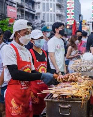 İnsanlar kömür ızgarasının üstünde mürekkep balığı ızgarası, markette kalamar balığı bbq, Çin kasabası Bangkok Tayland, Çin Mahallesi Temmuz 2022