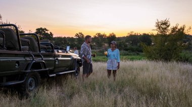 Asian women and European men on safari game drive in South Africa Kruger national park. a couple of men and women on safari. Tourist in a jeep looking sunset on safari