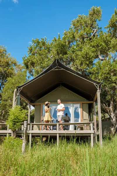 couple on safari in South Africa, Asian women and European men at a tented camp lodge during the safari. Couple of men and a woman are on vacation in South Africa