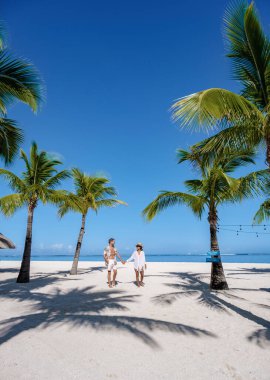 Le Morne plajı Mauritius Tropikal plajı. Palmiye ağaçları ve beyaz kum mavisi okyanus. Tatil sırasında sahilde yürüyen çift ve kadın.
