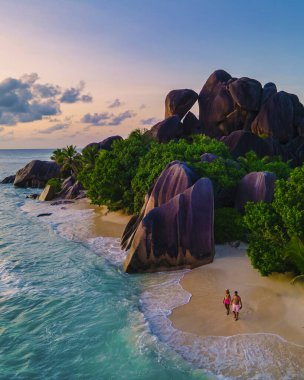Anse Source dArgent, La Digue Seychelles, Anse Source DArgent, La Digue Seychelles 'de lüks bir tatil sırasında tropikal bir plajda yaşayan birkaç beyaz erkek ve Asyalı kadın.