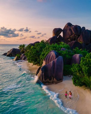 Anse Source dArgent, La Digue Seychelles, Anse Source DArgent, La Digue Seychelles 'de lüks bir tatil sırasında tropikal bir plajda yaşayan birkaç beyaz erkek ve Asyalı kadın.