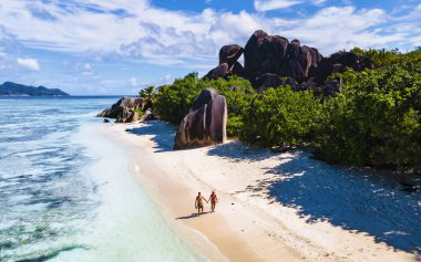 Anse Source dArgent, La Digue Seychelles, Anse Source DArgent, La Digue Seychelles 'de lüks bir tatil sırasında tropikal bir plajda yaşayan birkaç beyaz erkek ve Asyalı kadın.