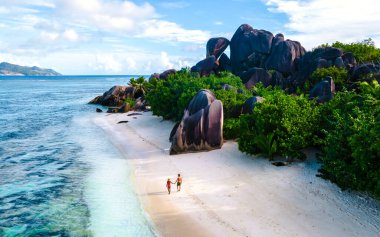 Anse Source dArgent, La Digue Seychelles, Anse Source DArgent, La Digue Seychelles 'de lüks bir tatil sırasında tropikal bir plajda yaşayan birkaç beyaz erkek ve Asyalı kadın.