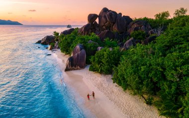 Anse Source dArgent, La Digue Seychelles, Anse Source DArgent, La Digue Seychelles 'de lüks bir tatil sırasında tropikal bir plajda yaşayan birkaç beyaz erkek ve Asyalı kadın.