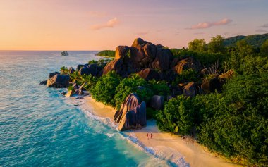 Anse Source dArgent, La Digue Seychelles, Anse Source DArgent, La Digue Seychelles 'de lüks bir tatil sırasında tropikal bir plajda yaşayan birkaç beyaz erkek ve Asyalı kadın.