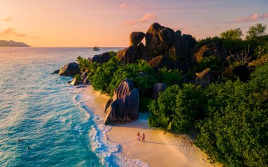 Anse Source dArgent, La Digue Seychelles, Anse Source DArgent, La Digue Seychelles 'de lüks bir tatil sırasında tropikal bir plajda yaşayan birkaç beyaz erkek ve Asyalı kadın.